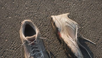 Worn neutral running shoes photographed from above on grey asphalt in morning light
