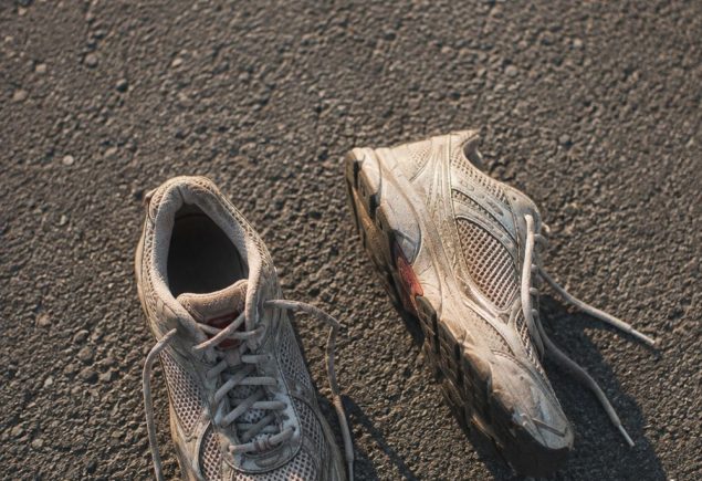 Worn neutral running shoes photographed from above on grey asphalt in morning light
