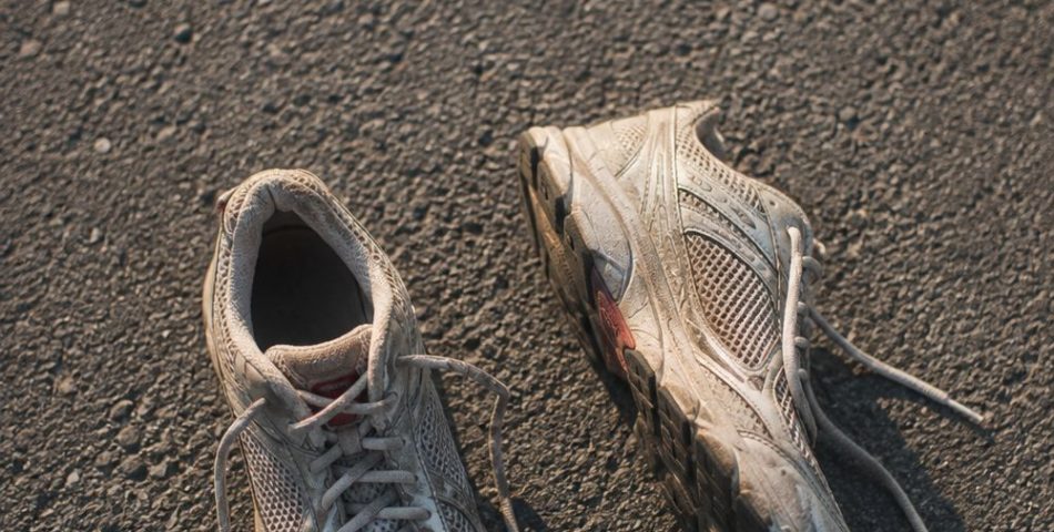 Worn neutral running shoes photographed from above on grey asphalt in morning light