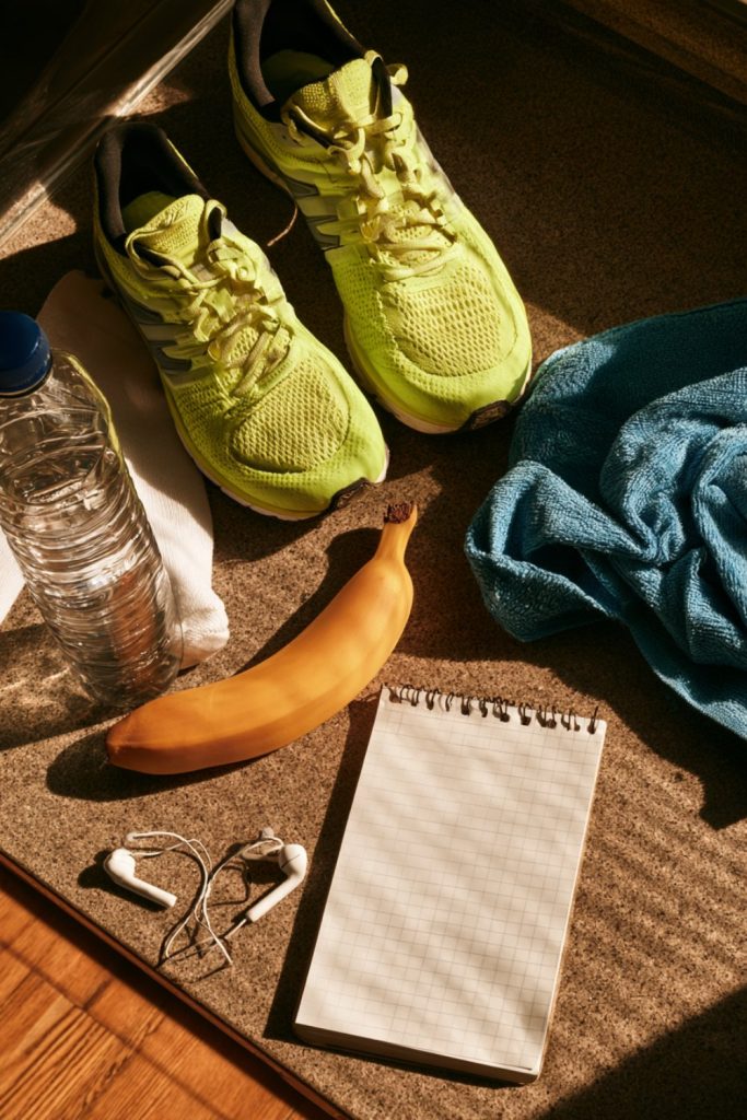 Running shoes, water, a banana and a blank notebook laid out before a training run