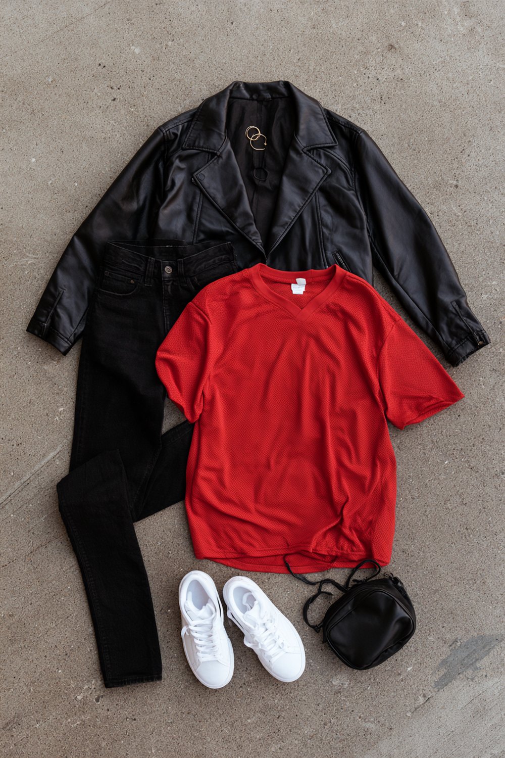 All-black basketball game look with a red tee: leather jacket, black skinny jeans, white sneakers and a mini crossbody