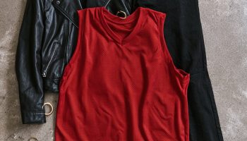 Basketball game outfits for women flat lay with a black leather jacket, red mesh jersey top, black jeans, white sneakers and a small black crossbody bag