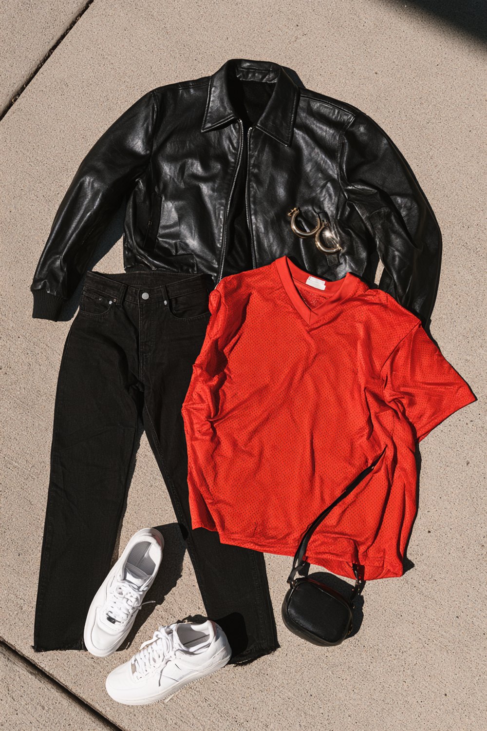 Casual basketball game outfit: red v-neck tee, black jeans, black leather jacket, simple white sneakers and gold hoops