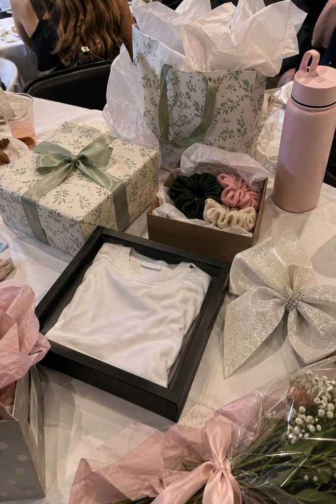 Gift table after a cheer banquet with a framed practice shirt, oversized bow, scrunchies, water bottle and wrapped boxes