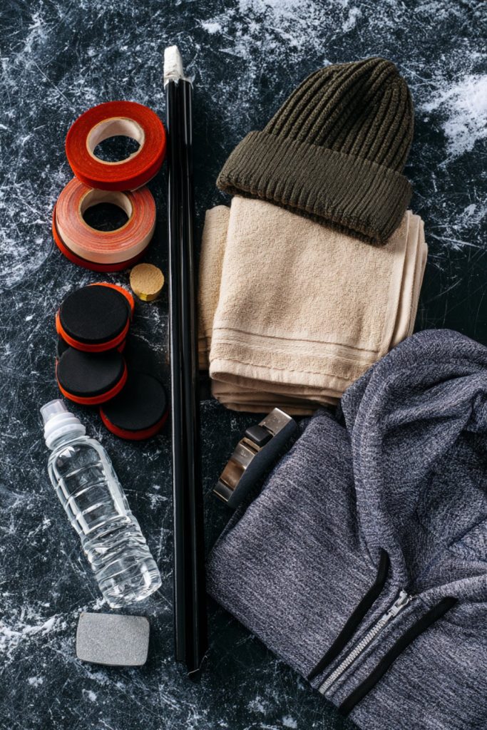 Red and black stick tape, a knit beanie and a folded hoodie as gifts for a hockey player
