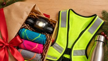 Gifts for runners flat lay with running socks, headlamp, reflective vest, water bottle and foam roller wrapped for Christmas