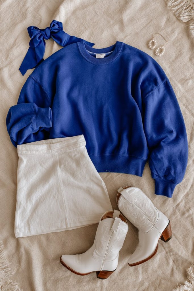Royal blue and white game day flat lay with a hair bow and white denim