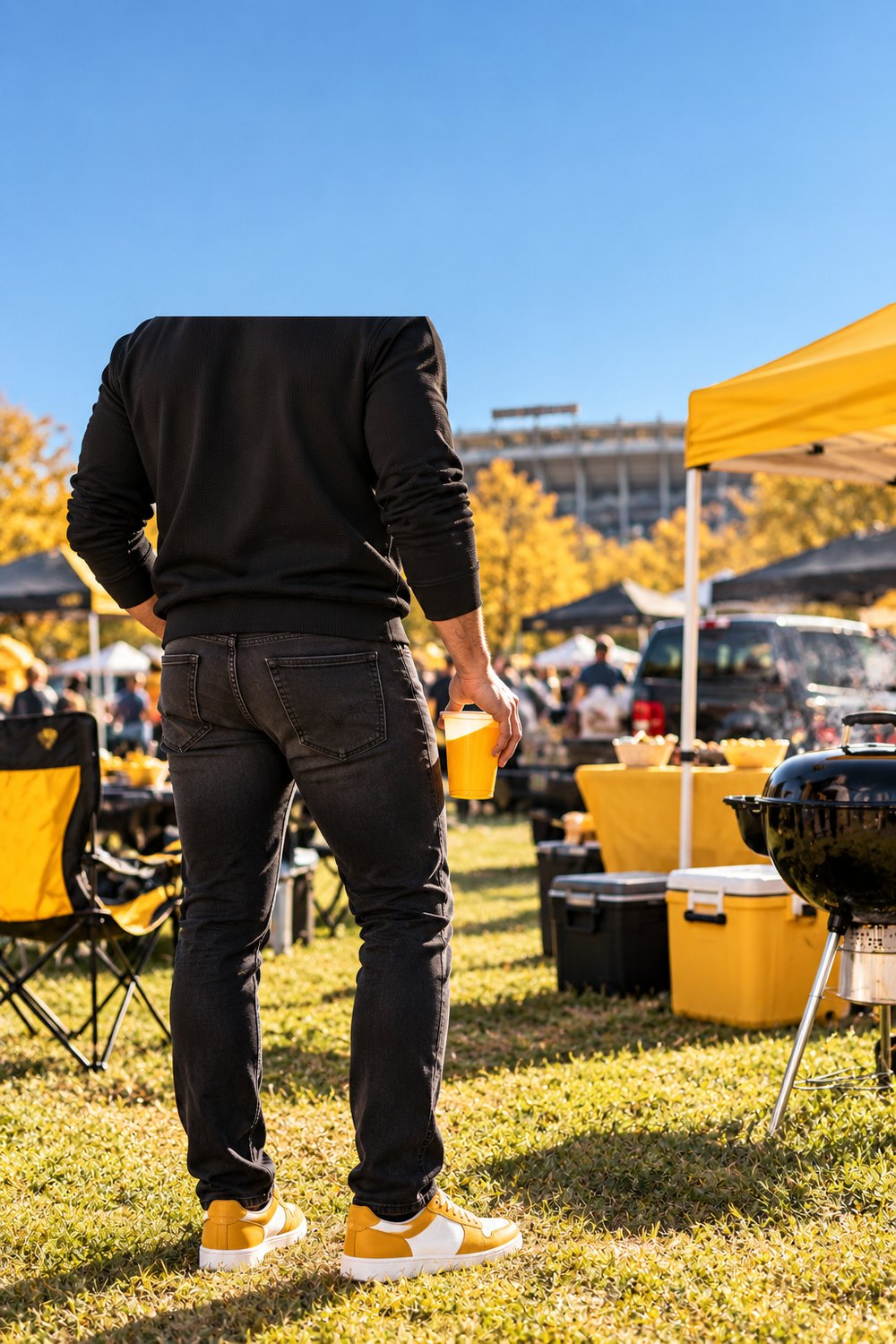 Men's Mizzou game day outfit with a black quarter-zip, dark jeans and gold sneakers at a tailgate