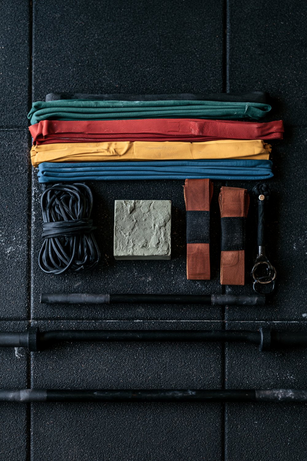 Pull up progression gear: stacked resistance bands, chalk blocks and grips on a gym floor