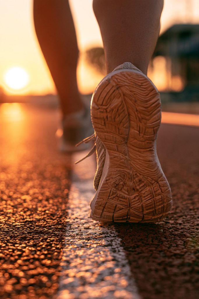 Runner's heel lifting off a sunlit running track