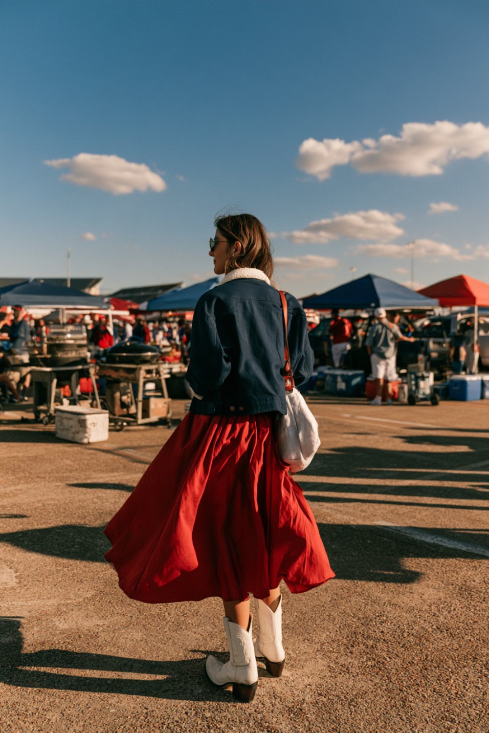 Woman from behind in navy and red with white boots at a sunny stadium tailgate